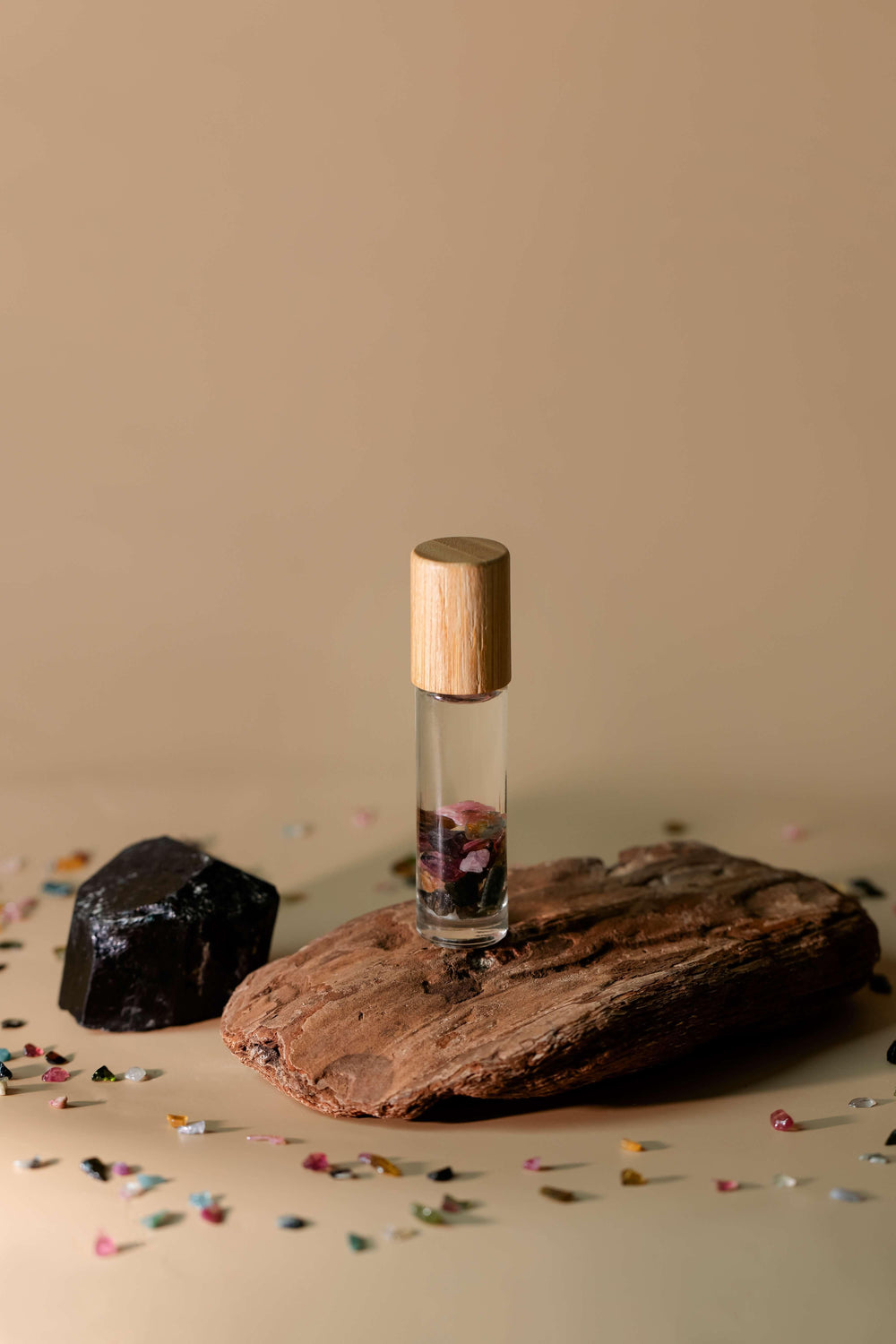 Clear oil roller on raised rock platform with black and watermelon tourmaline